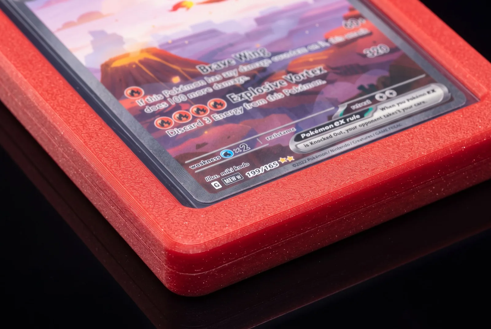 Close-up of a Scarlet Alpha Loader corner: a squared-off frame with a wide flat border and a fine sparkle texture around a top loader